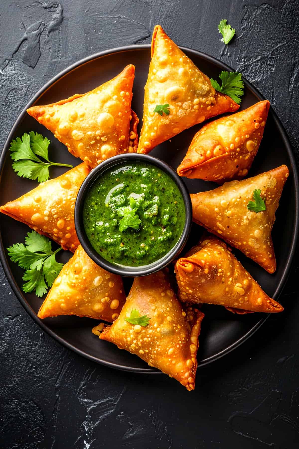 Healthy green chutni in a bowl served with samosas.