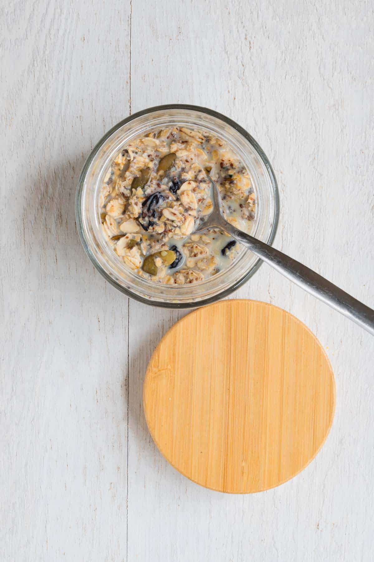 Ground flaxseeds, hemp hearts, dried tart cherries, prunes, oat bran, rolled oats, chia seeds, and hemp hearts with nondairy milk in a jar.