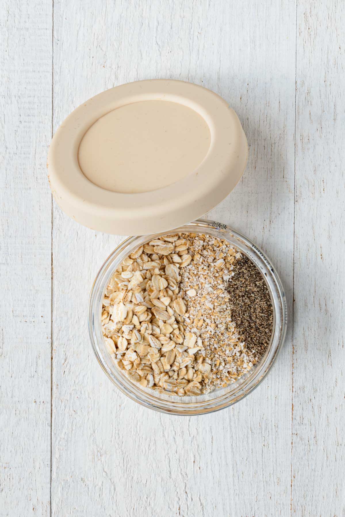 Rolled oats, oat bran, and ground chia seeds in a glass container.