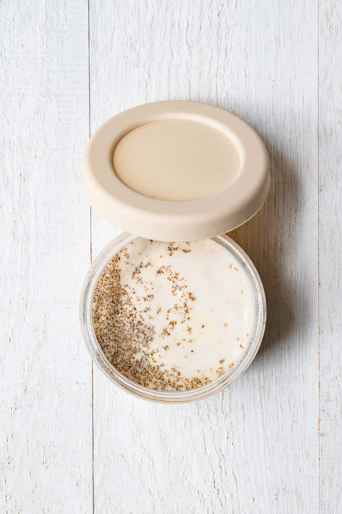 Rolled oats, oat bran, ground chia seeds, nondairy milk, and Greek yogurt in a glass container.