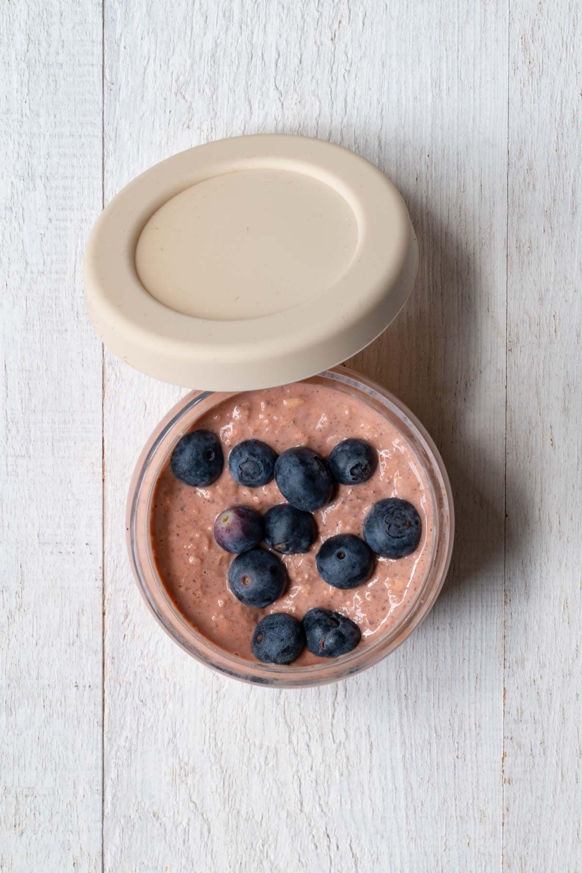 Overnight oats with beet powder in a glass container with blueberries.