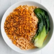 Tofu Peanut Noodles with baby bok choy in a white bowl.