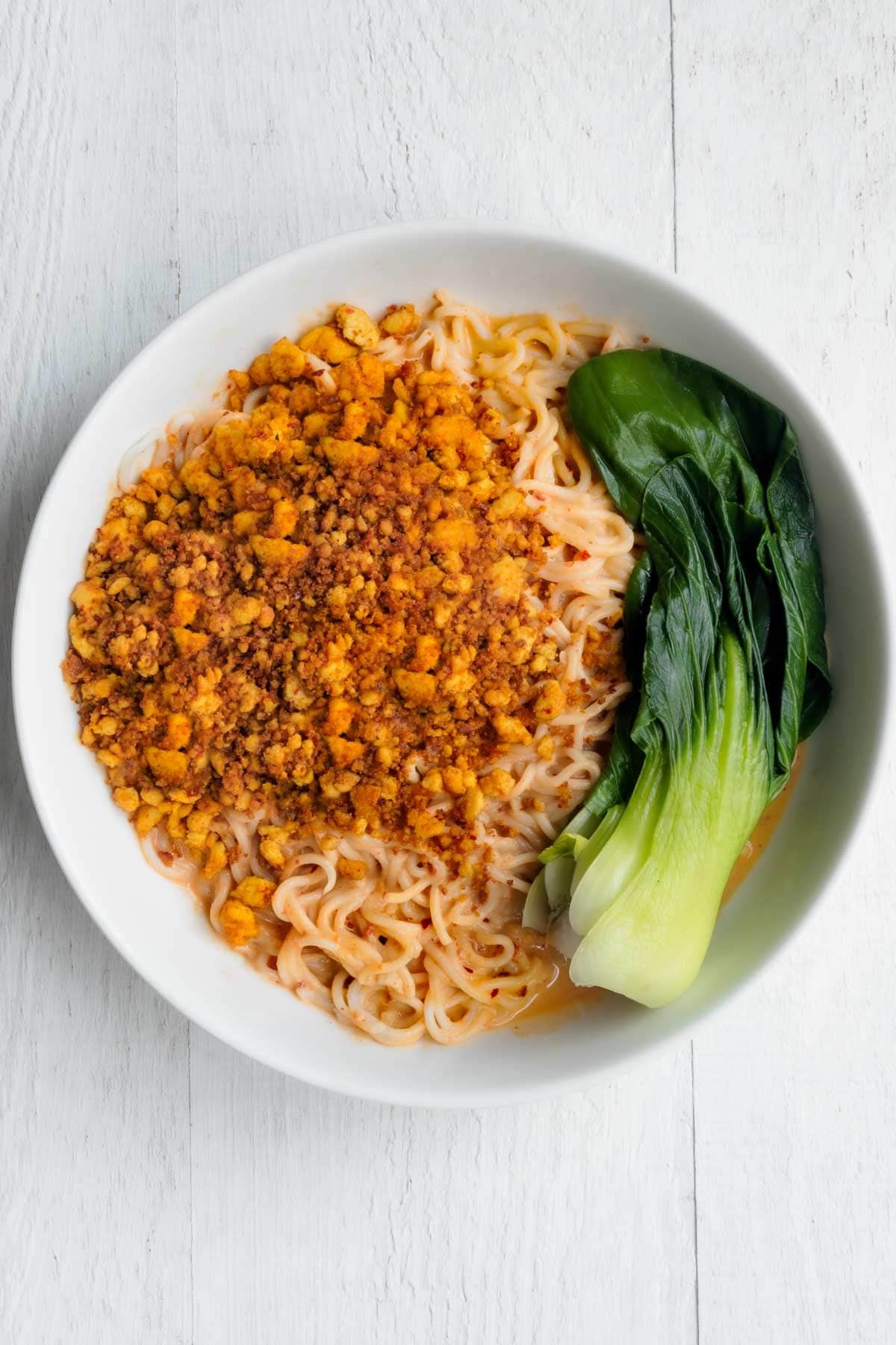 Tofu Peanut Noodles with baby bok choy in a white bowl.
