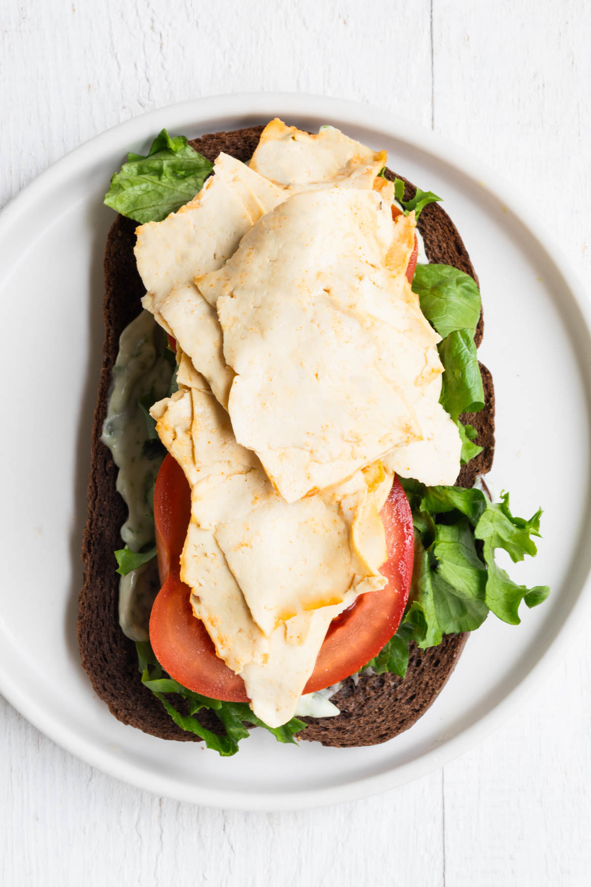 Vegan deli meat on an open face sandwich.