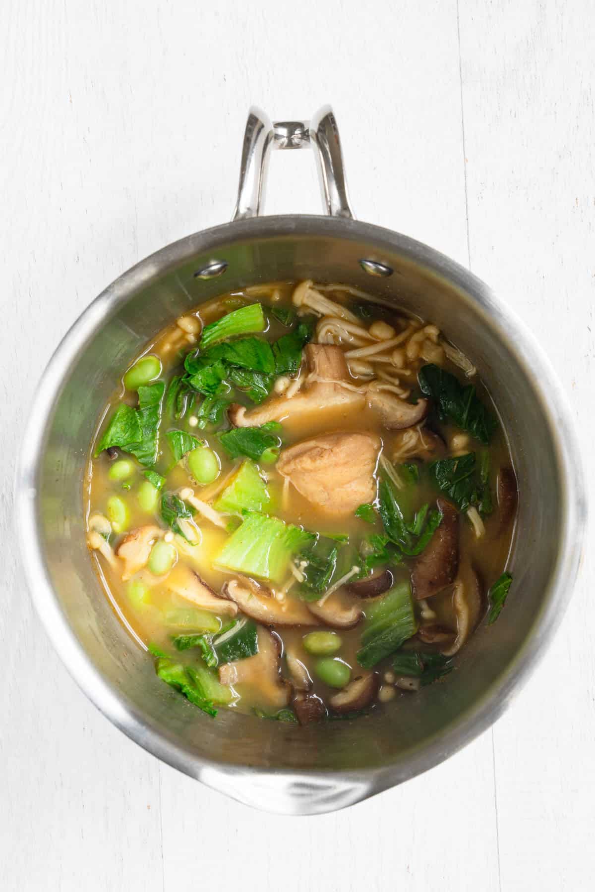 Veggie broth, seasonings, miso, mushrooms, bok choy, and edamame in a small saucepan.