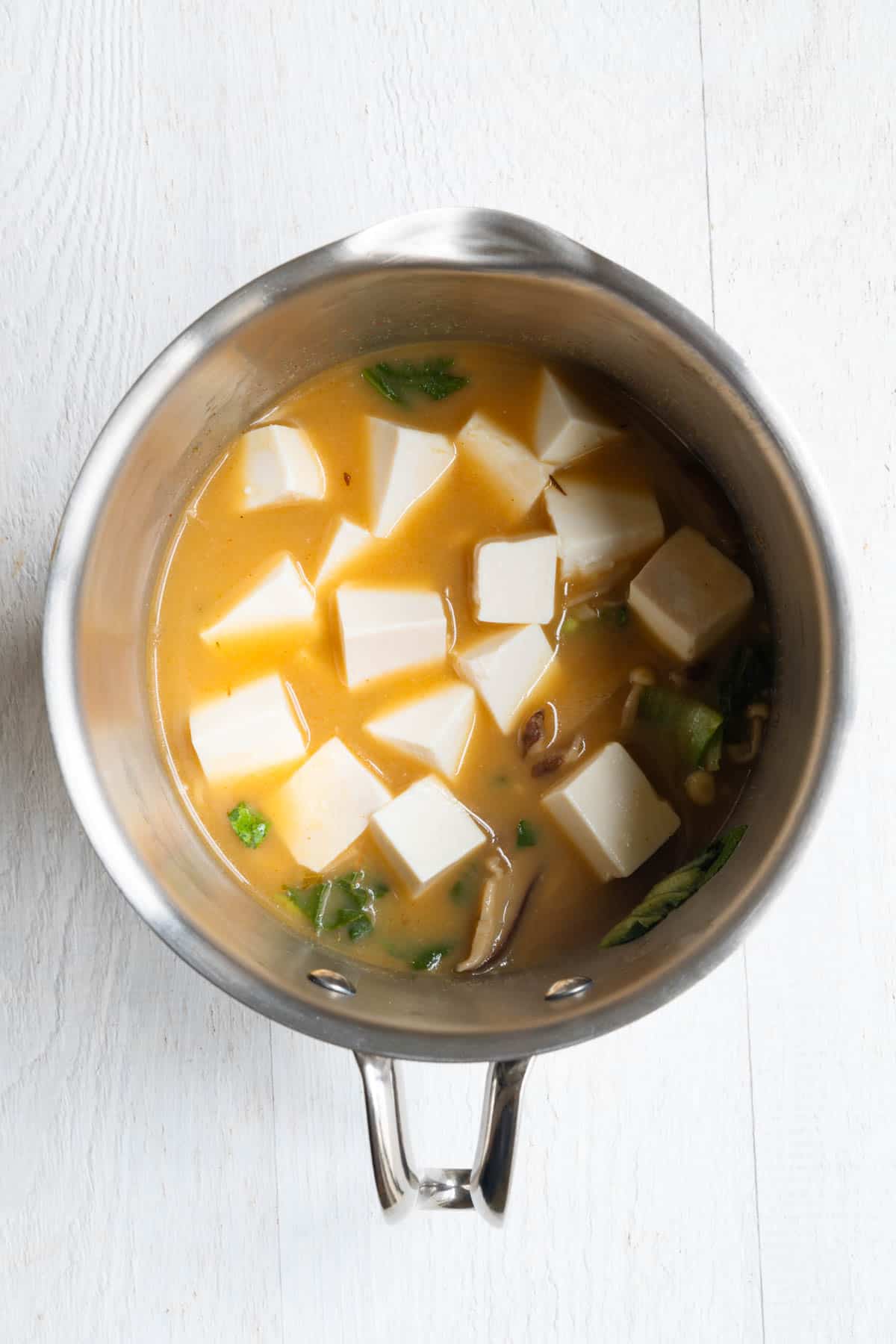 Veggie broth, seasonings, mushrooms, bok choy, edamame, and silken tofu in a small saucepan.