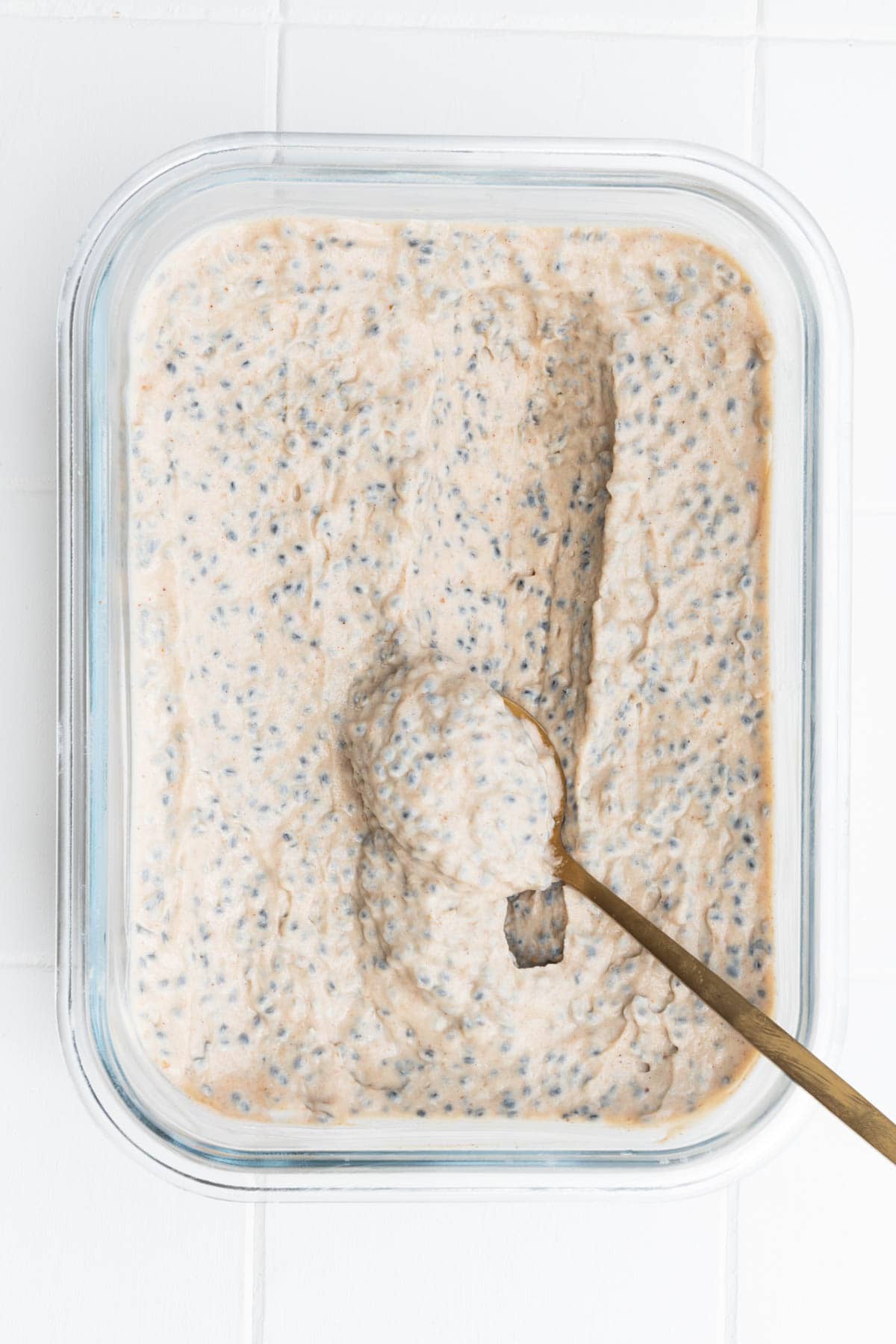 Banana chia seed porridge in a glass meal-prep dish.