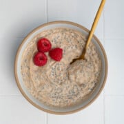 Banana chia seed porridge in a bowl topped with raspberries.