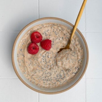 Banana chia seed porridge in a bowl topped with raspberries.