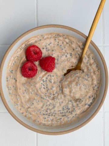 Banana chia seed porridge in a bowl topped with raspberries.
