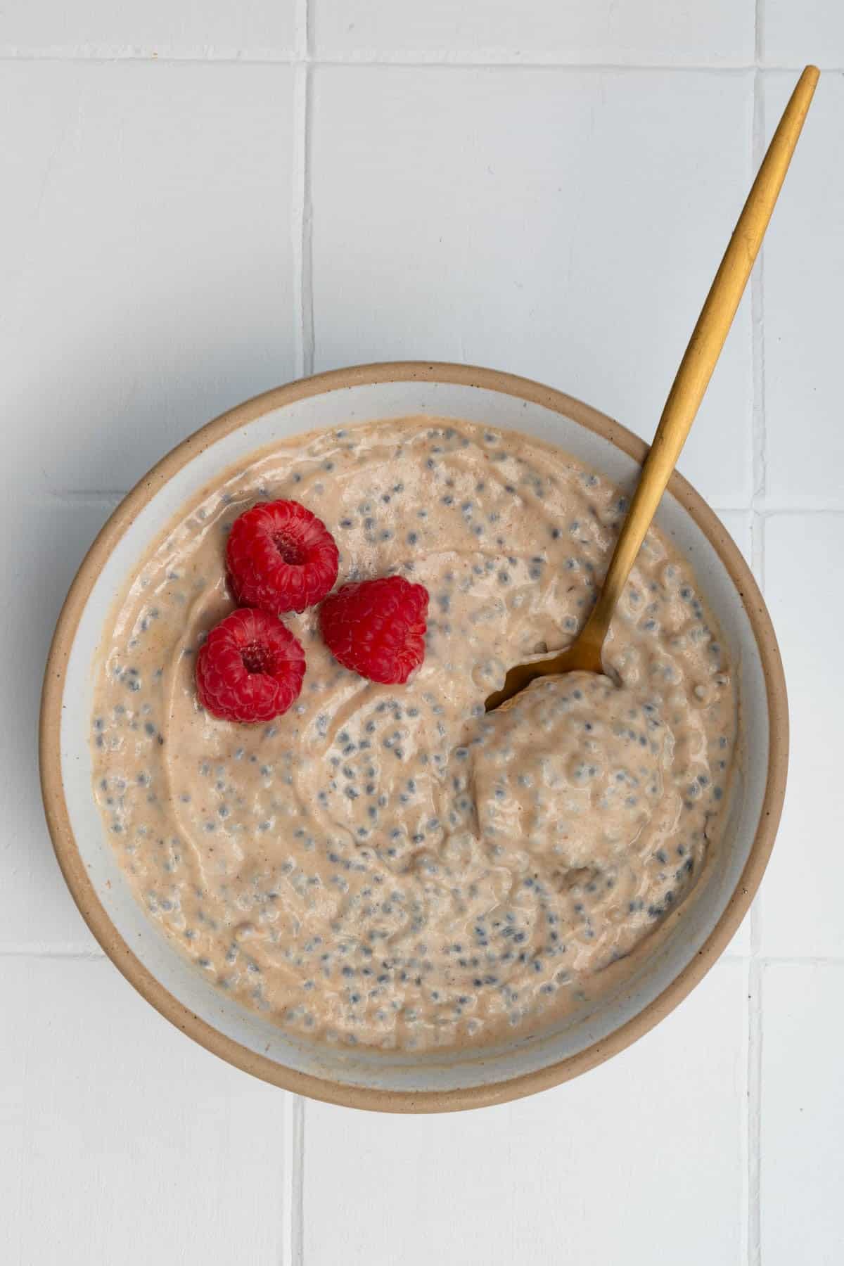 Banana chia seed porridge in a bowl topped with raspberries.