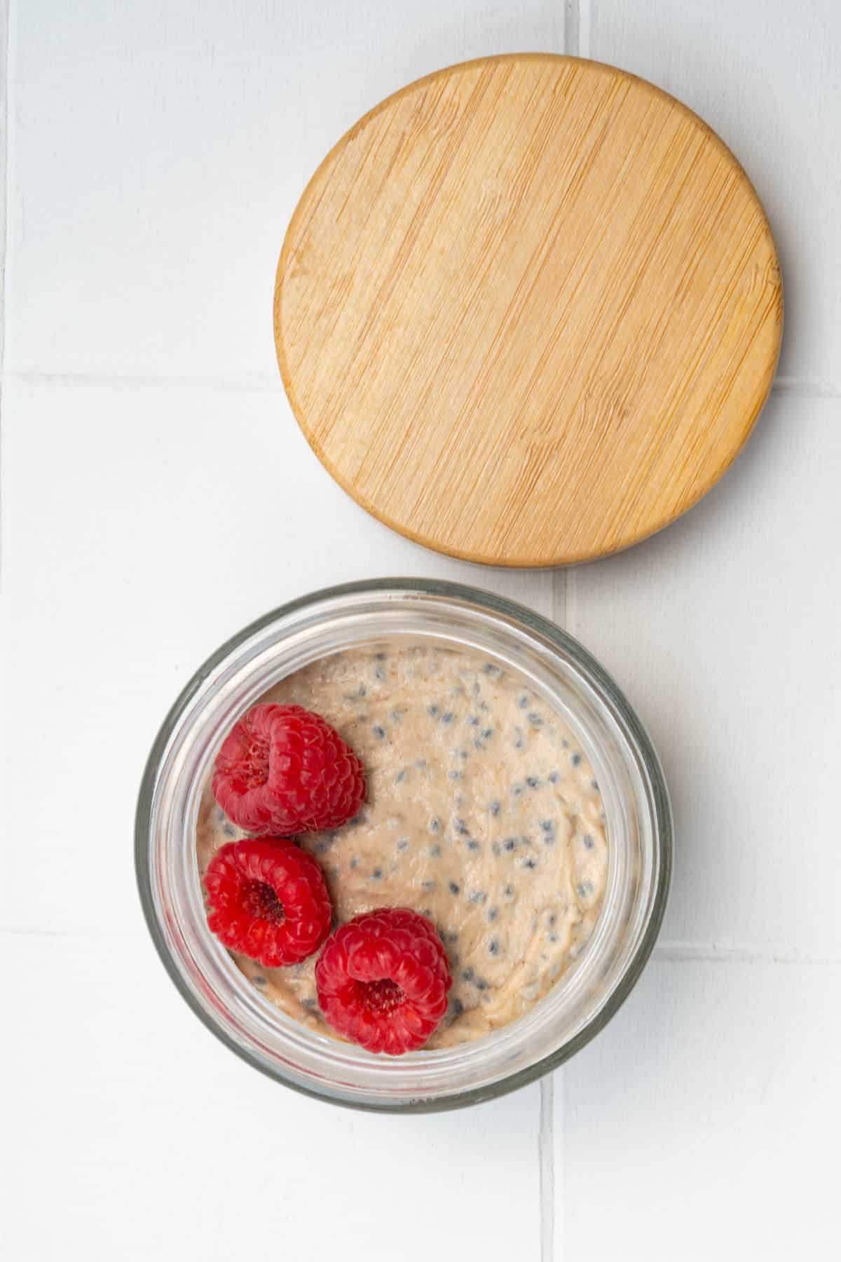Banana chia seed porridge in a jar with raspberries.