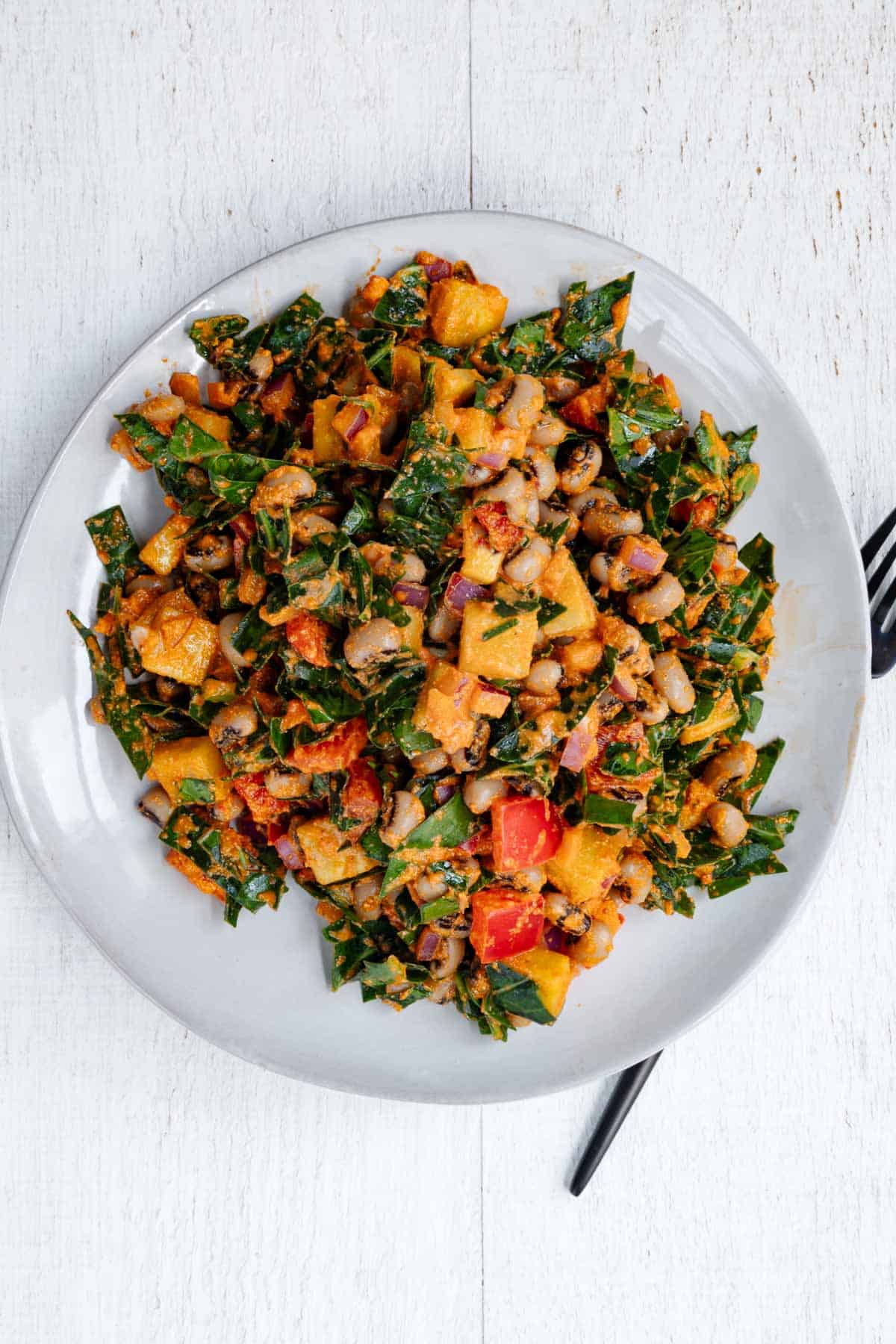 Black eyed peas salad on a white plate and a black fork.