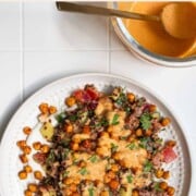 Chickpea Quinoa Mediterranean Salad on a white plate with creamy harissa dressing.