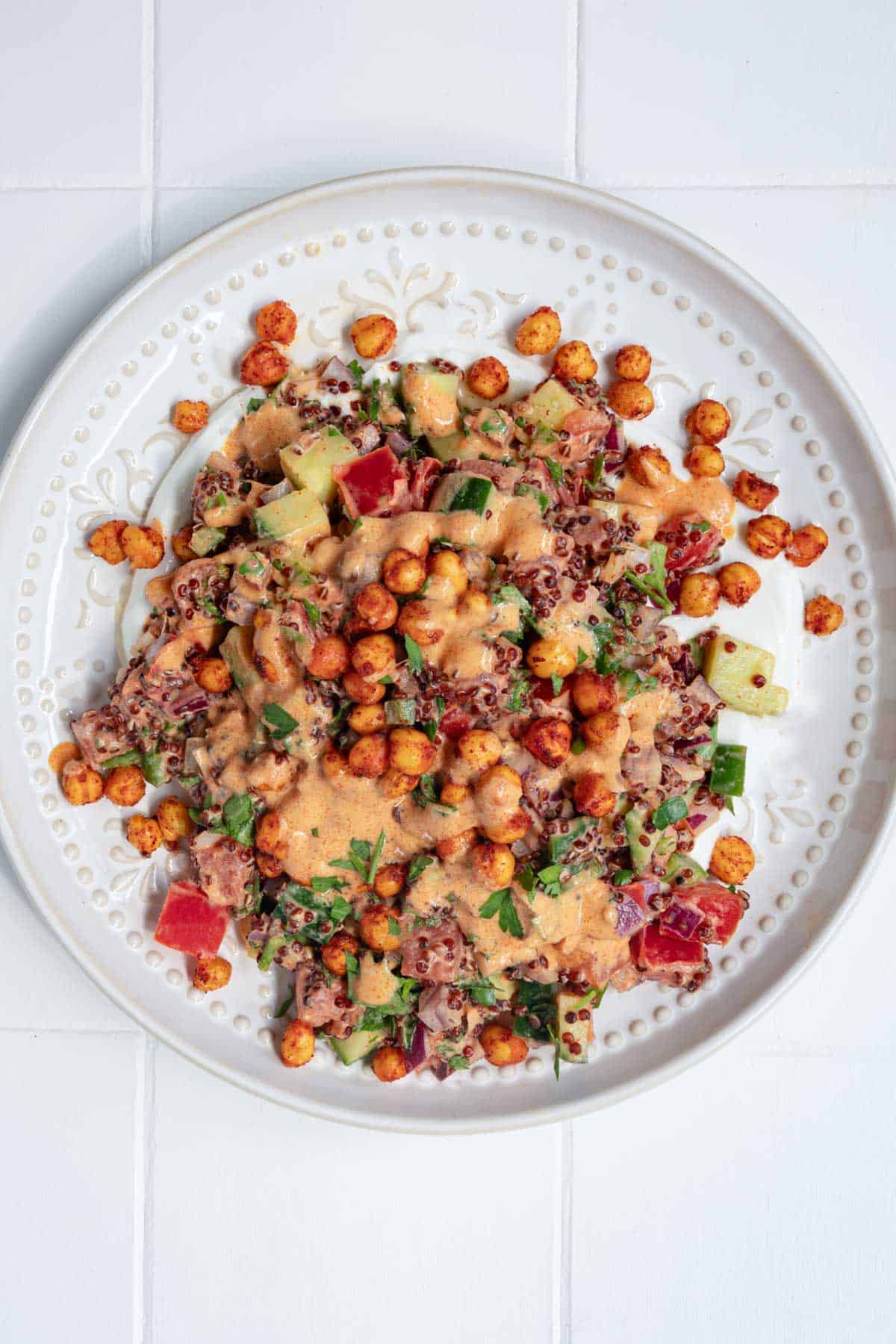 Creamy Oil-Free Quinoa Garbanzo Bean Salad on a white plate over yogurt.