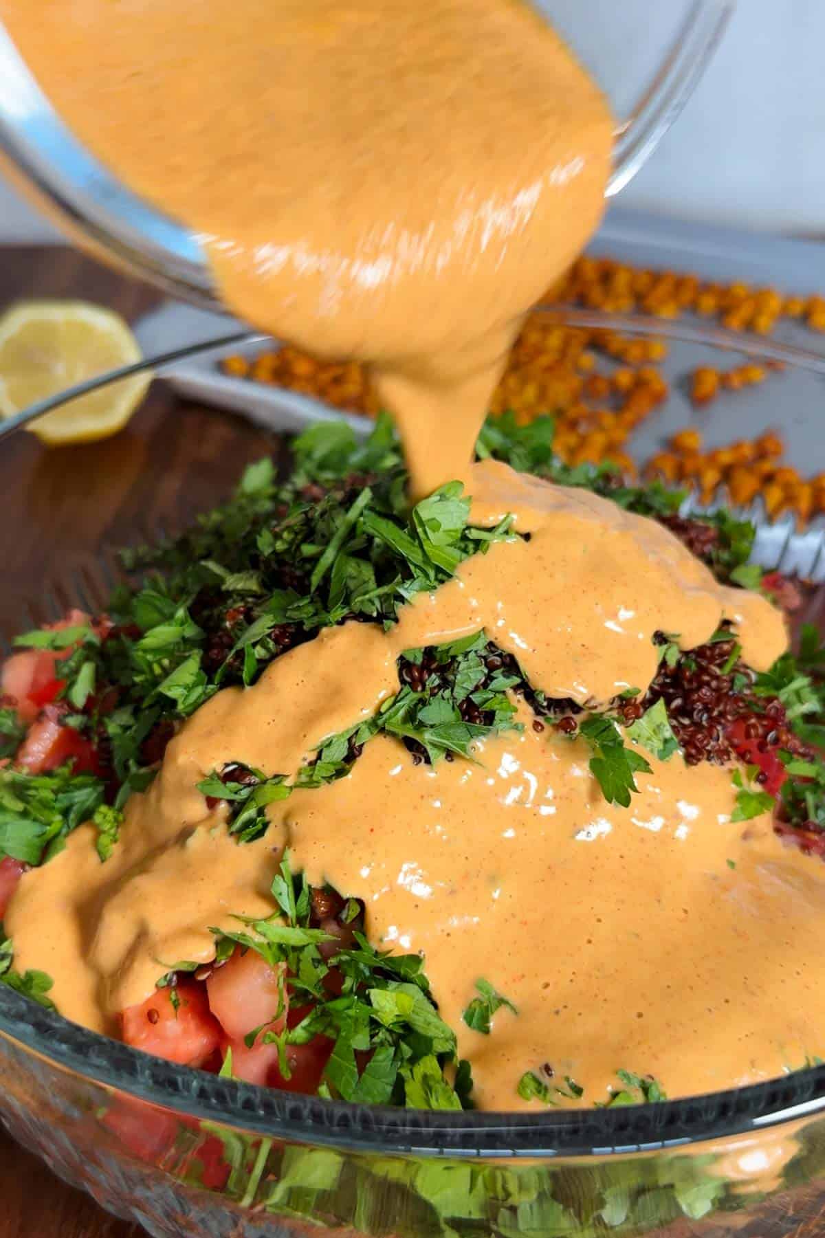 Pouring harissa dressing onto salad.