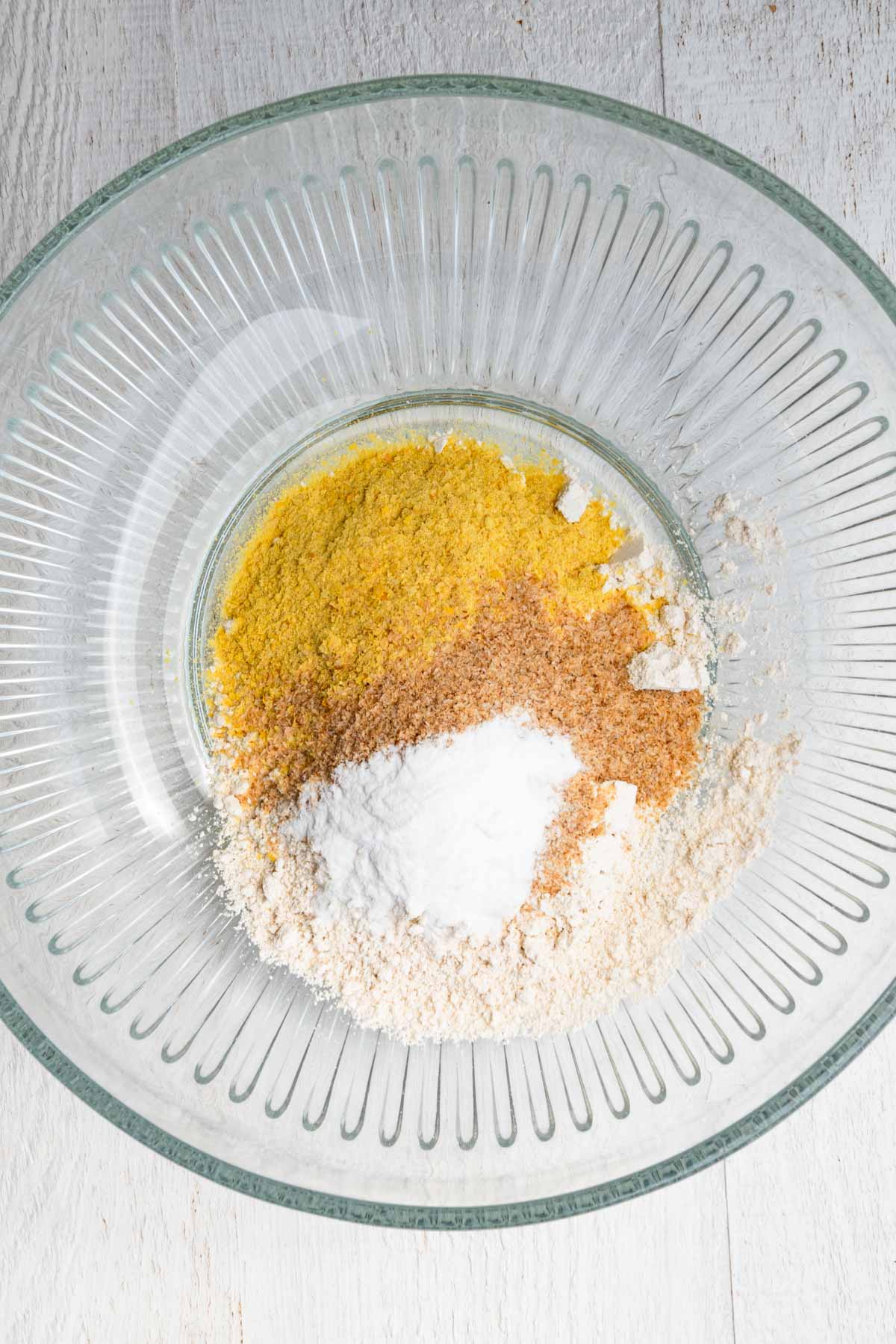 Oat flour, psyllium husk, nutritional yeast, and baking soda in a bowl.