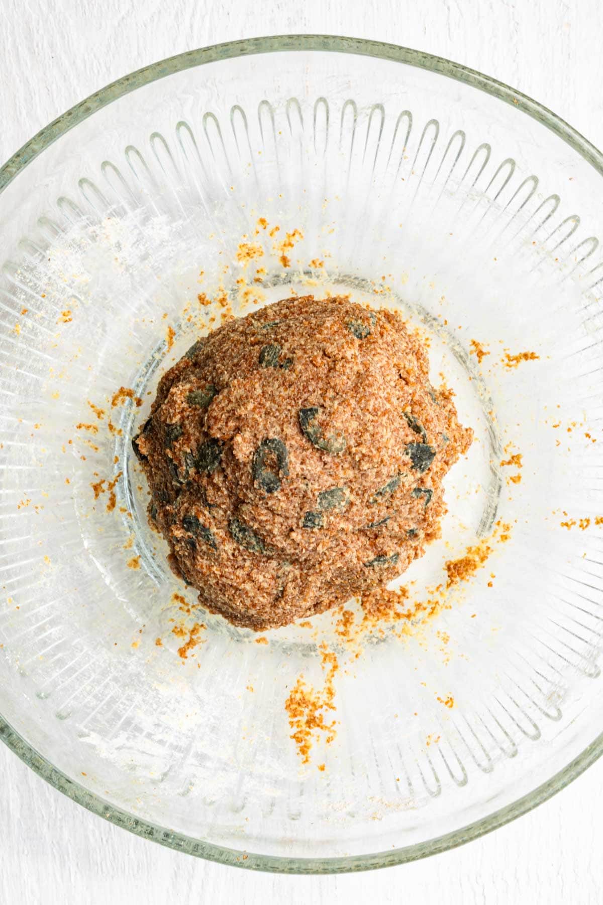 Gluten free dough rolled into a ball in a glass bowl.
