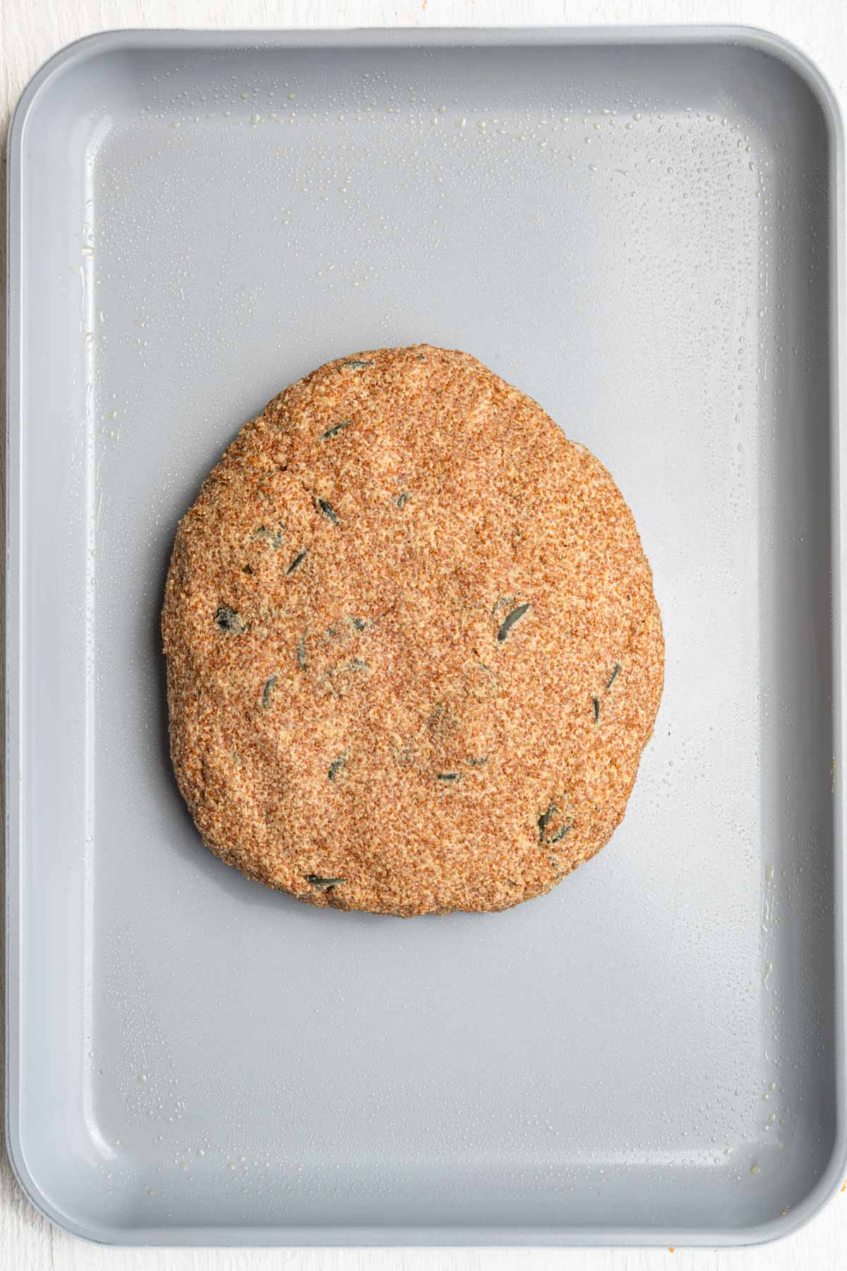 Gluten free teff dough shaped into an oval on a baking sheet.