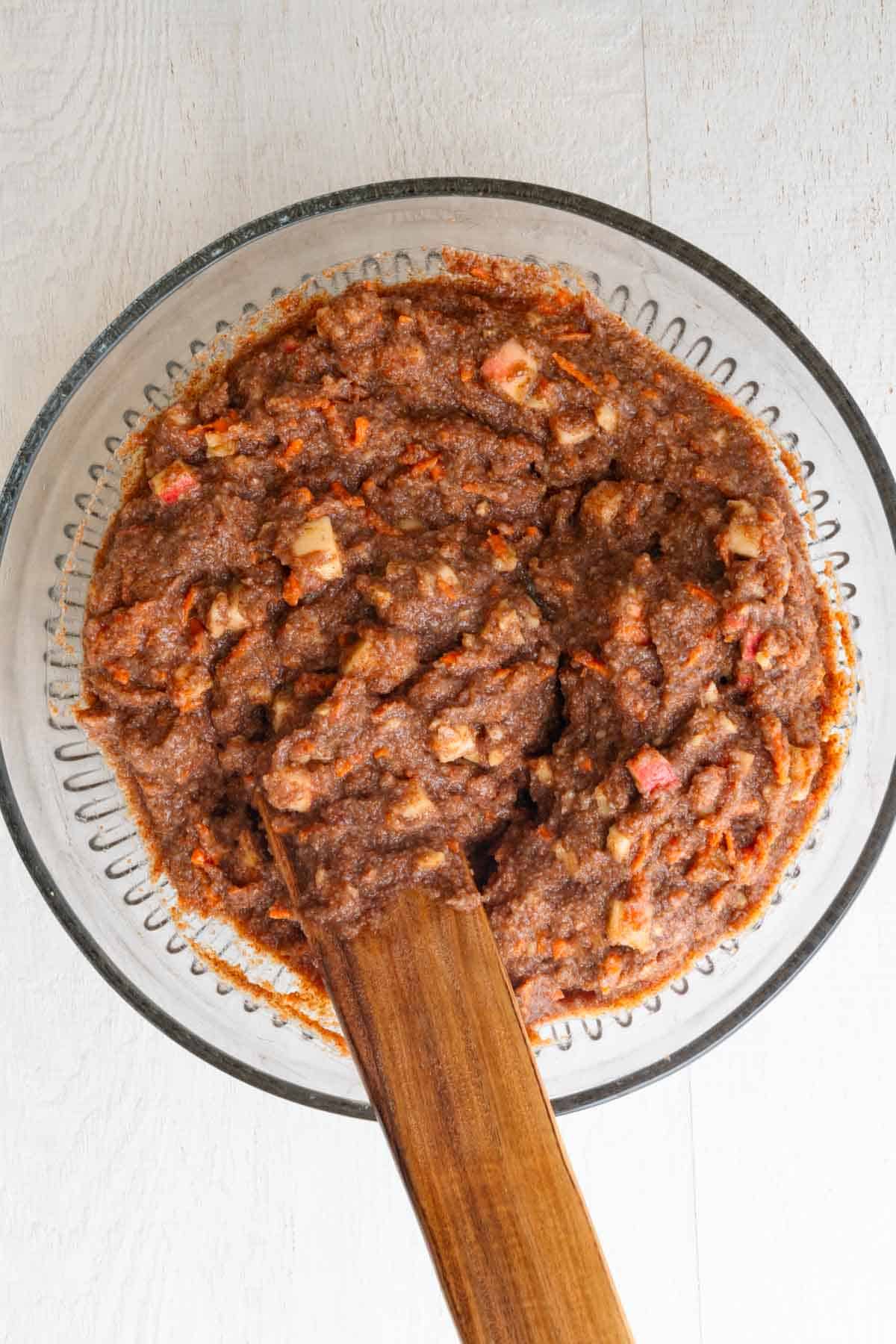 Cake batter in a glass bowl with a wooden spatula.