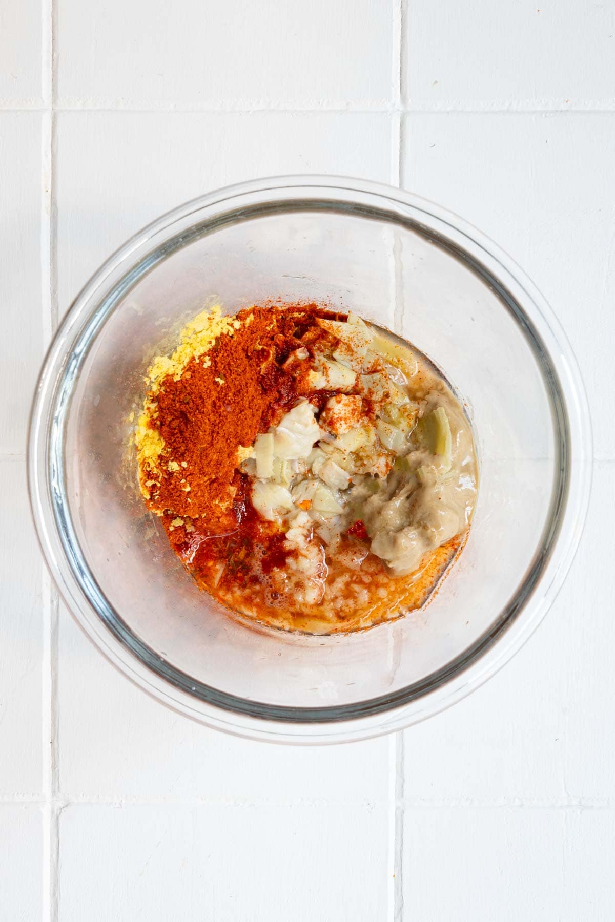 Artichoke hearts, lemon juice, nutritional yeast, harissa, maple syrup, and tahini in a glass jar.