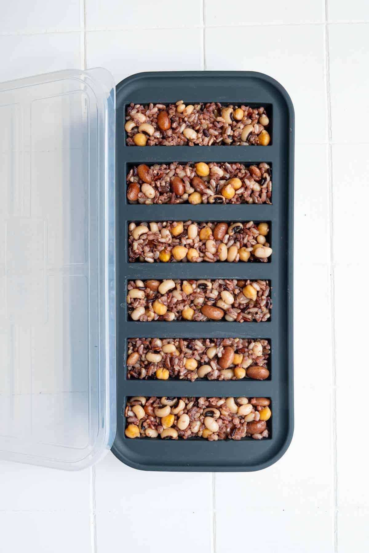 Cooked rice and beans divided into portions in a freezer-safe container.