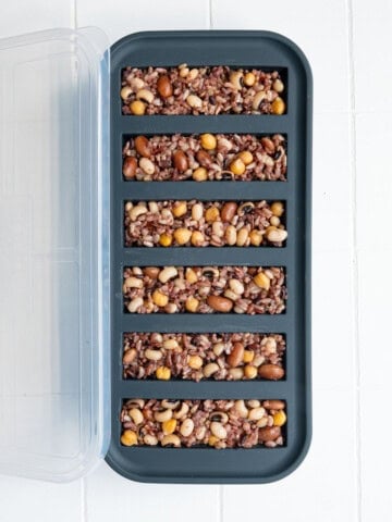 Cooked rice and beans divided into portions in a freezer-safe container.