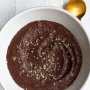 Teff porridge chocolate flavored in a white bowl.