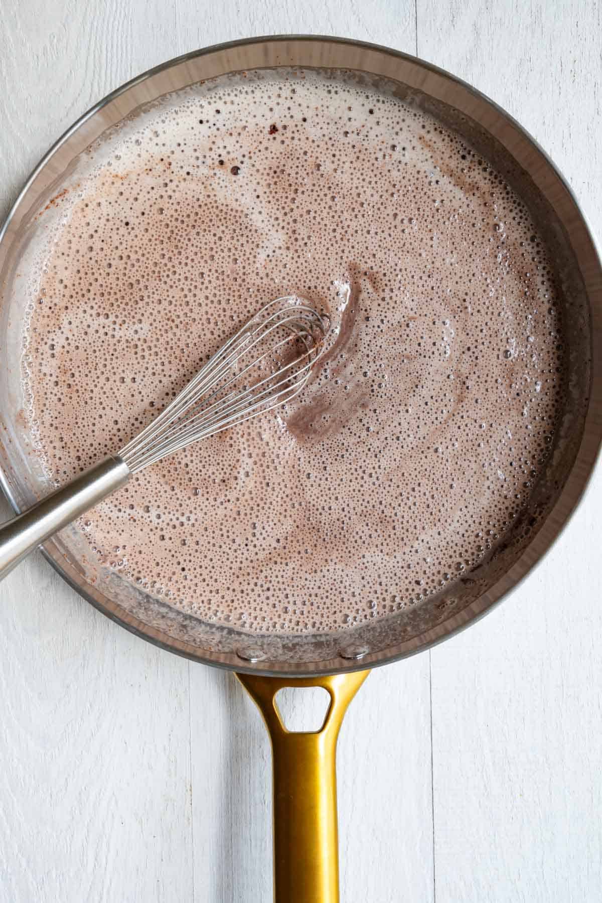 Teff, nondairy milk, cocoa powder, cinnamon, and cayenne cooking in a skillet.
