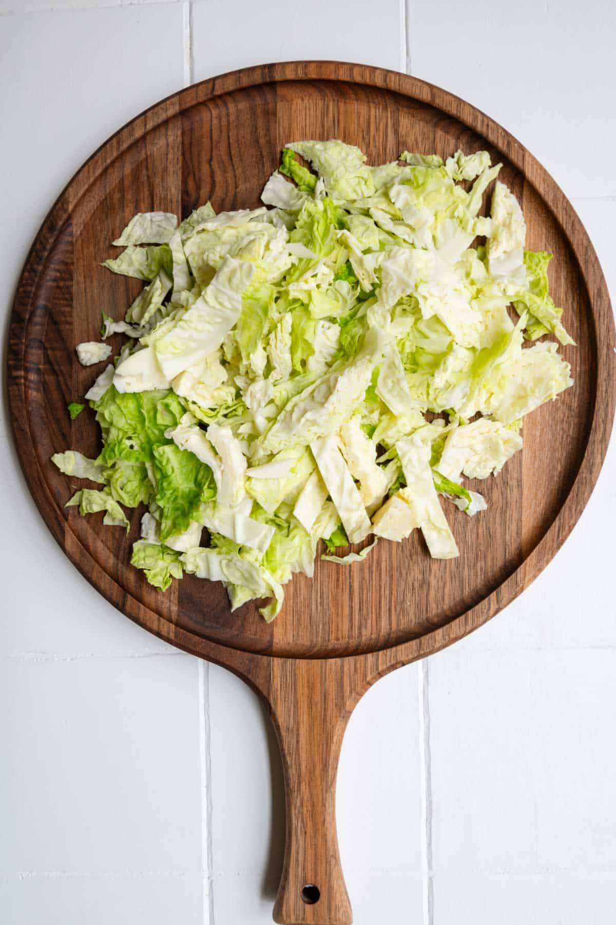 Sliced green cabbage on a wooden cutting board.