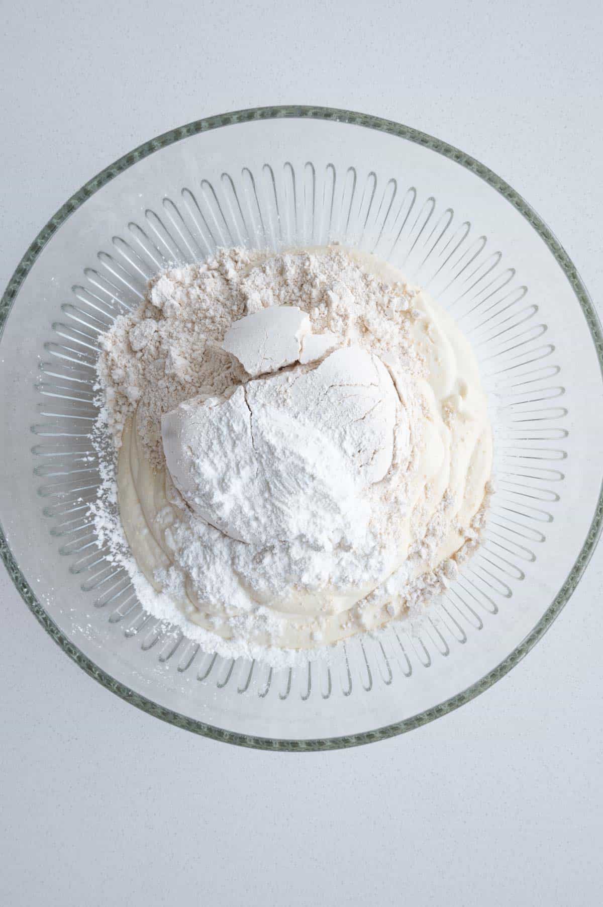 Flour, baking powder, blended yogurt and tofu in a glass bowl.