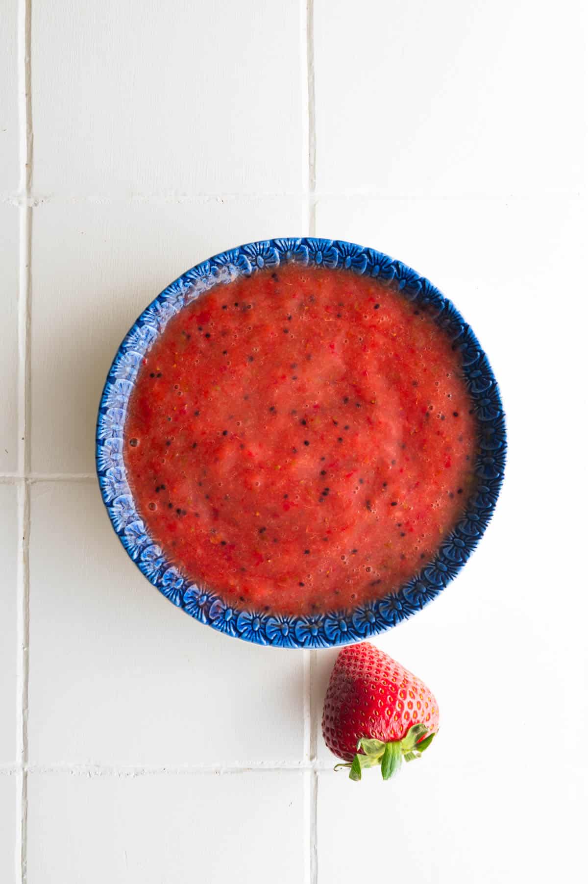 A ceramic garlic grater plate with mashed strawberry.