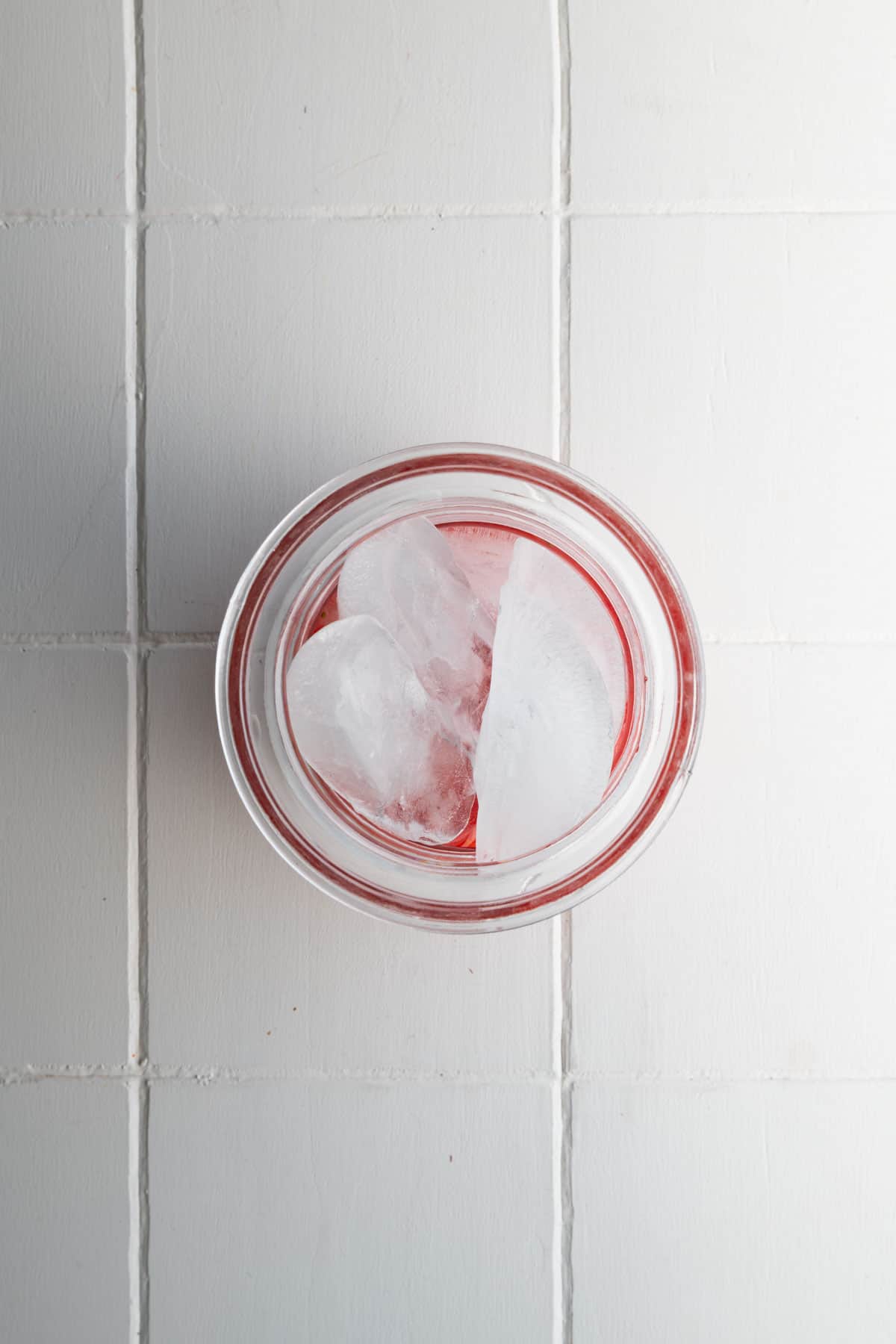 Pureed strawberry in a glass with ice and a straw.