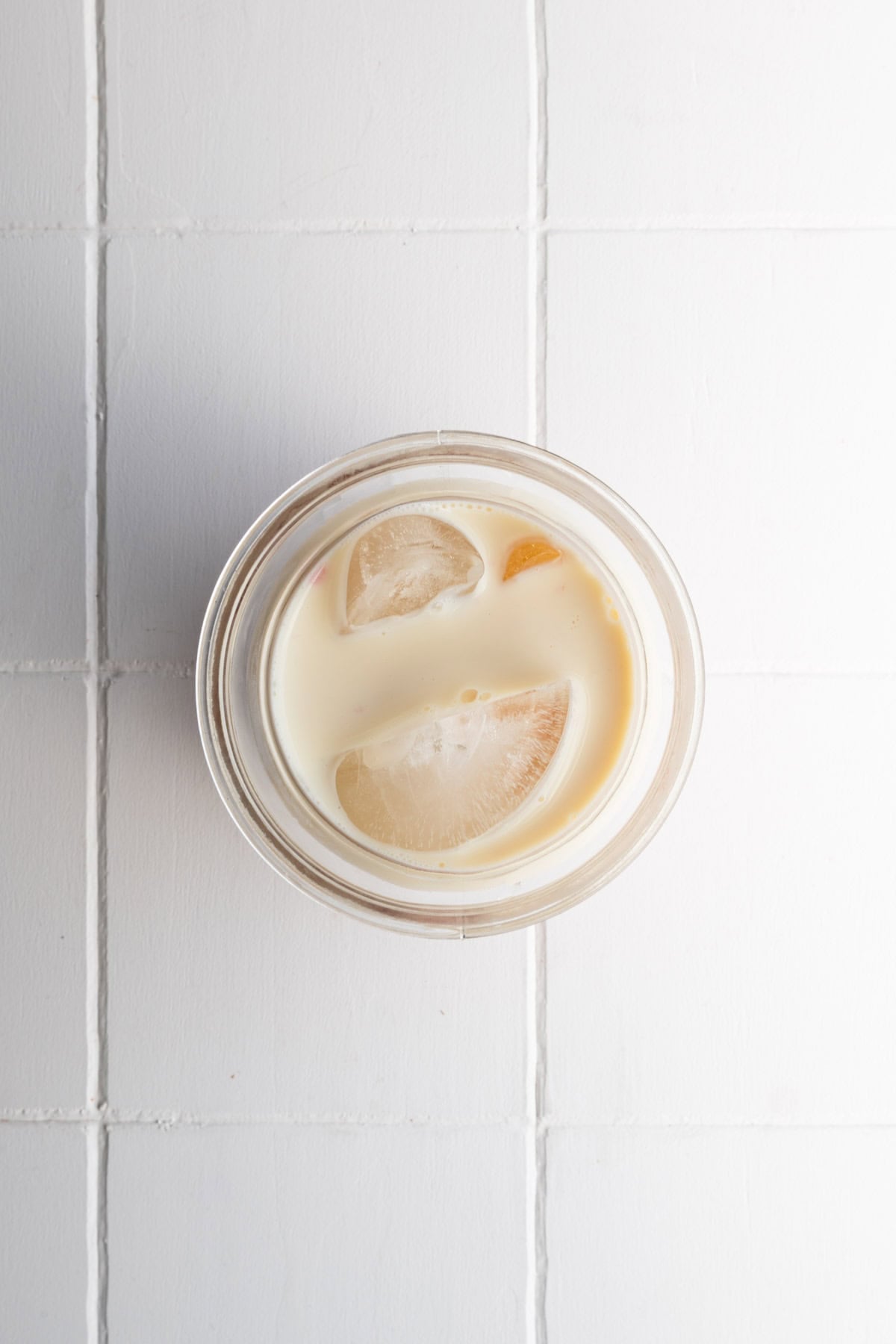 Nondairy milk in a glass with ice and a straw.