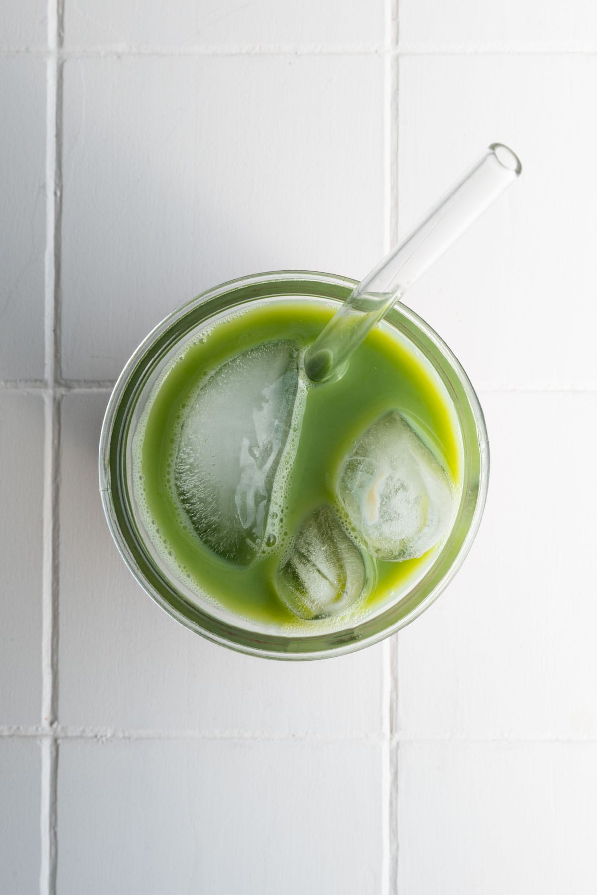 Strawberry matcha latte in a glass with ice and a straw.