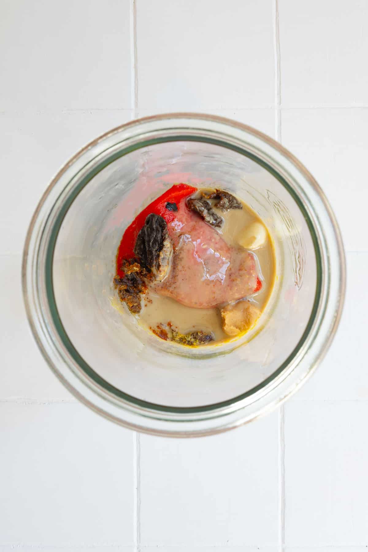 Sun-dried tomatoes, roasted red bell pepper, tahini, nutritional yeast, garlic, and vinegar in a jar.