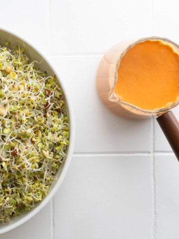 Sun-dried tomato dressing served with a bowl of sprouts.