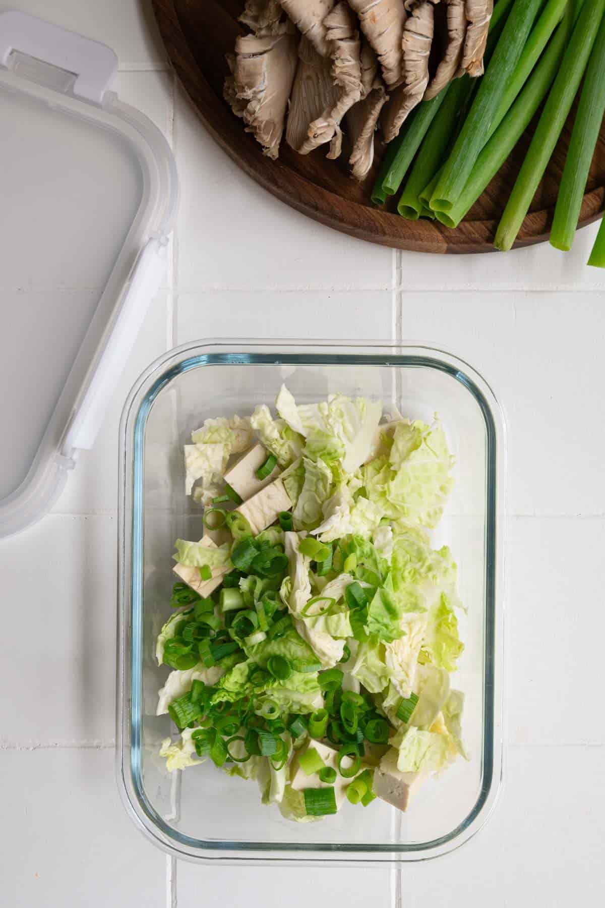 Sliced cabbage, green onion, and tofu in a glass dish.