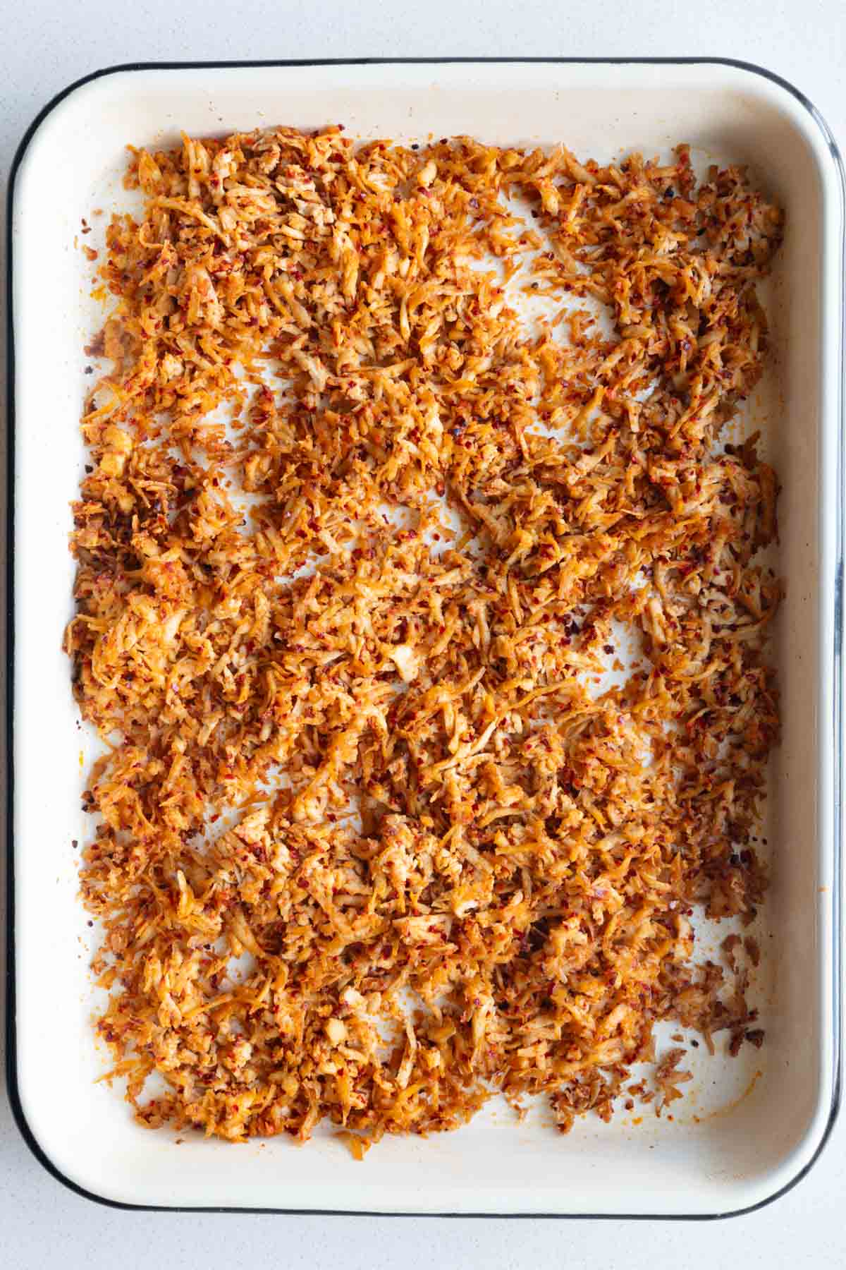 Baked grated tofu on a white sheet pan.