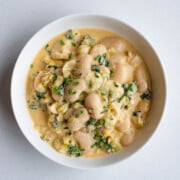 Creamy gigante beans with leek in a white bowl.