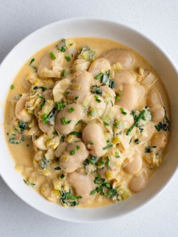 Creamy gigante beans with leek in a white bowl.