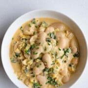 Creamy gigante beans with leek in a white bowl.