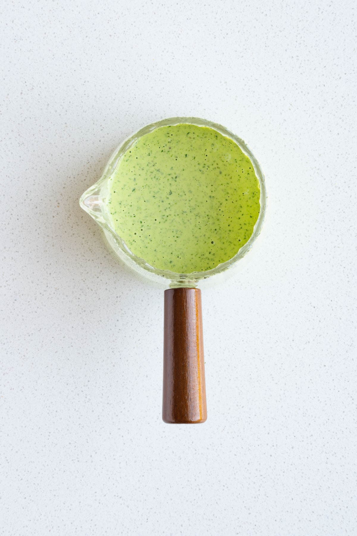 Tahini green goddess dressing in a glass jar.