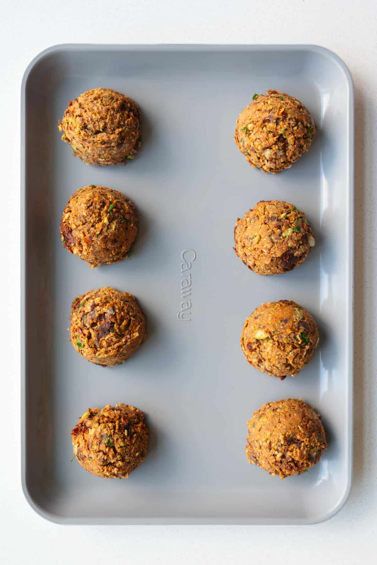 Eight scooped patties on a baking sheet.