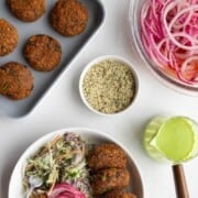 Edamame black bean burgers with pickled red onion, sweet potatoes, creamy coleslaw, green goddess dressing, and hemp hearts.
