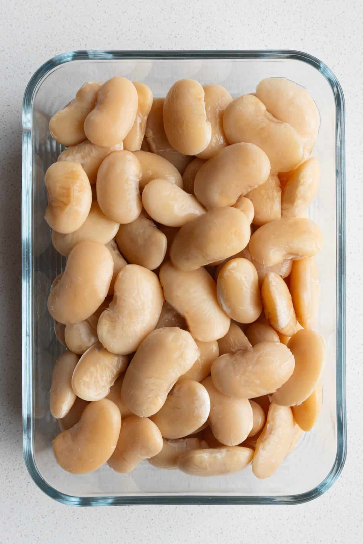 Cooked Gigantes beans (giant beans, giant greek beans, giant white beans, γίγαντεσ, greek gigante beans) in a glass container.