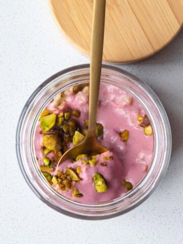 Oat groats breakfast parfait in a jar with a spoon.