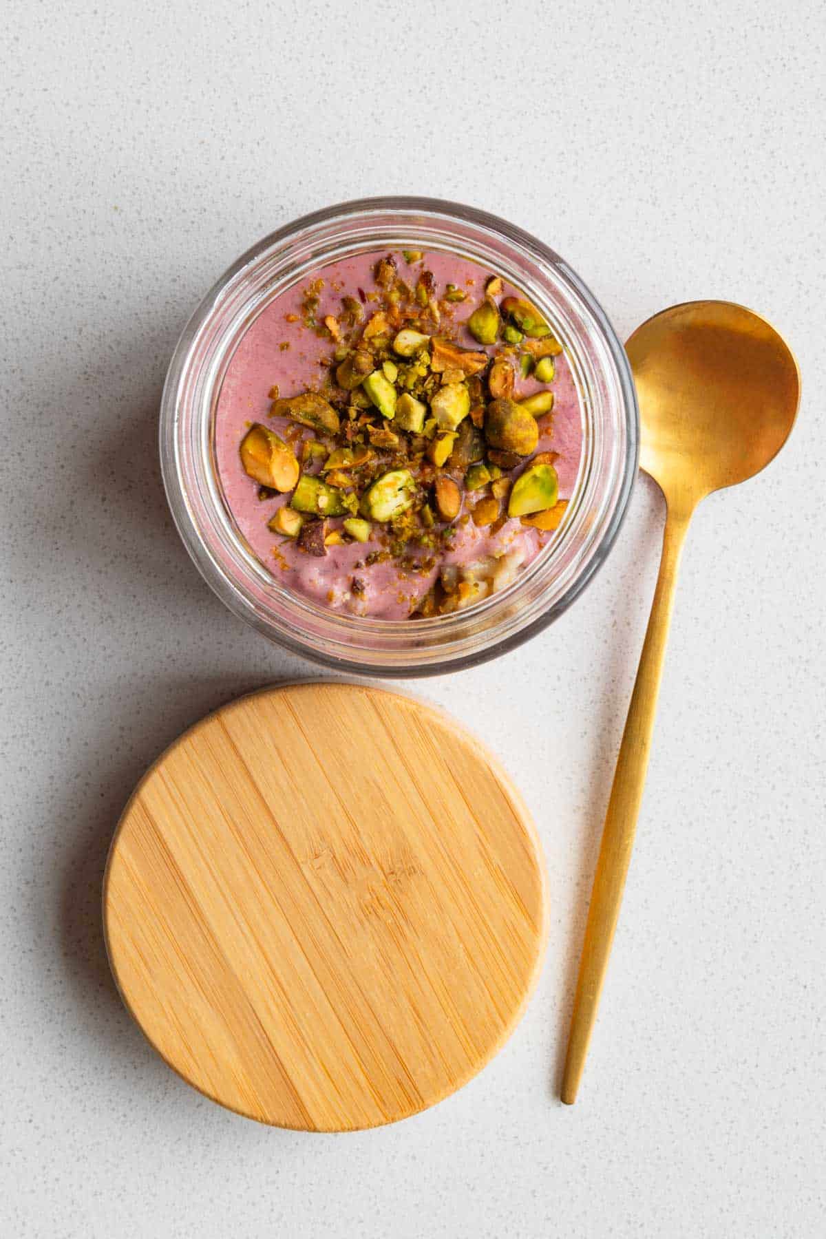 Oat groats breakfast parfait in a jar topped with chopped nuts.