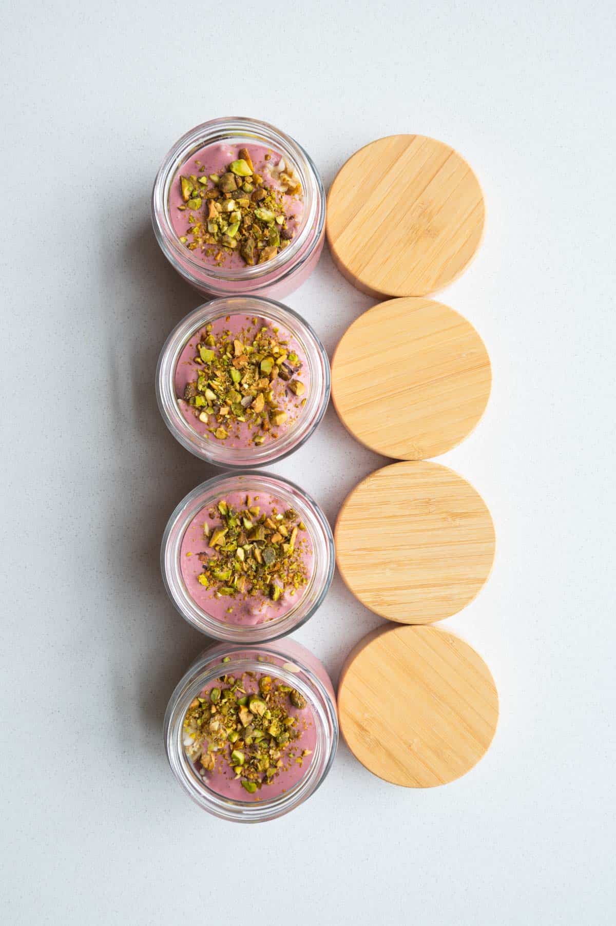 Oat groats parfaits in 4 jars topped with chopped pistachios.