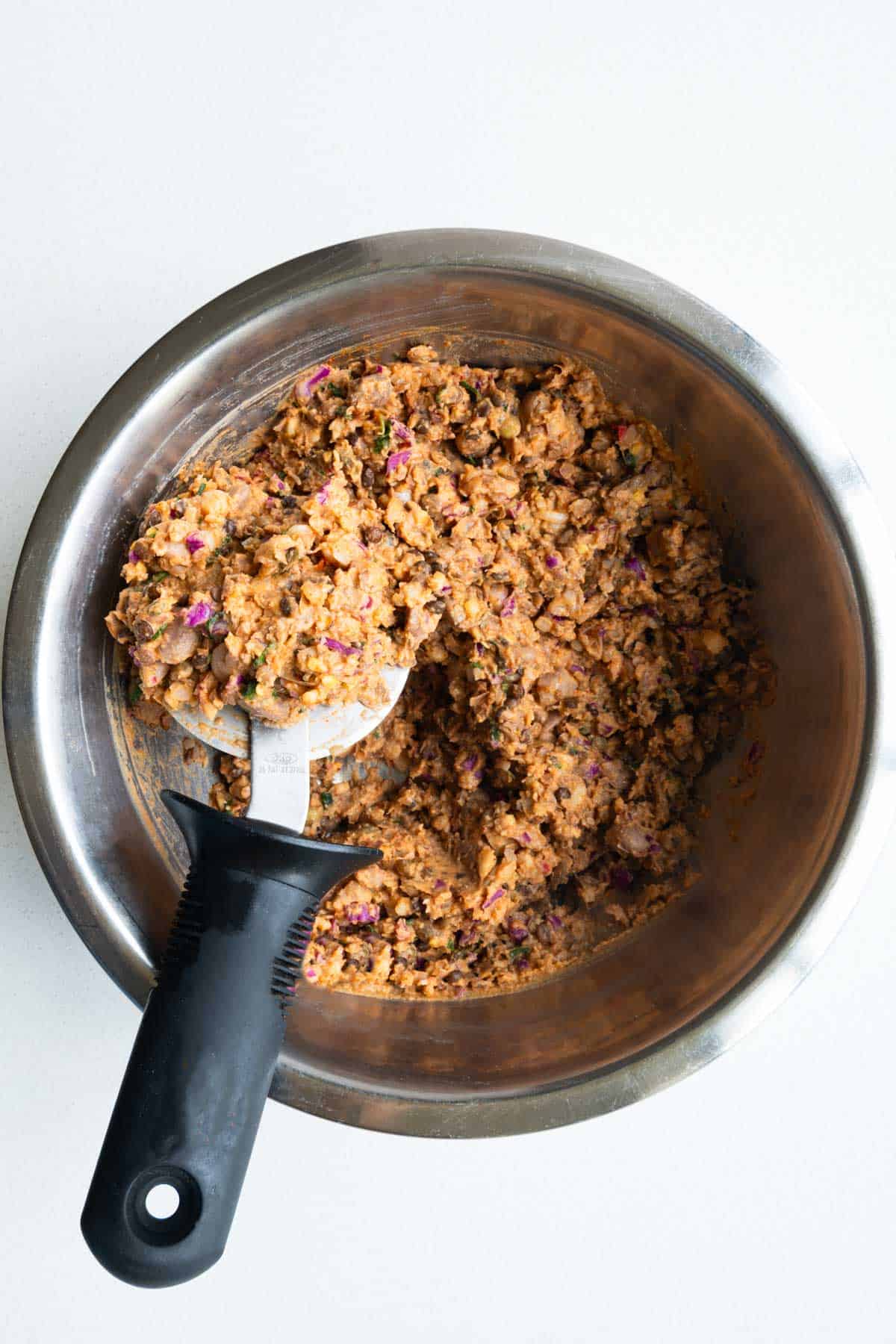 Mashed mixture with a pizza cutter in a metal bowl.